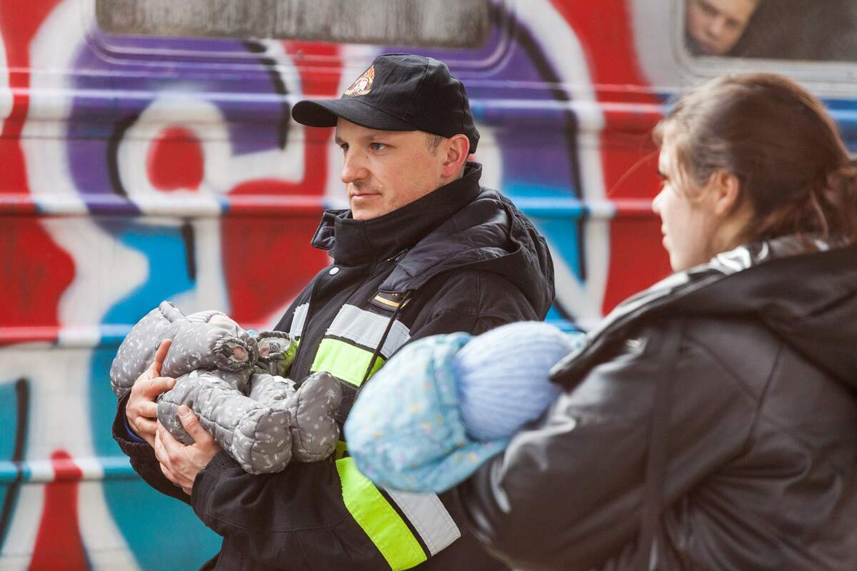 Pompier polonais avec un enfant ukrainien dans ses bras. Mirek Pruchnicki via Wikimédia