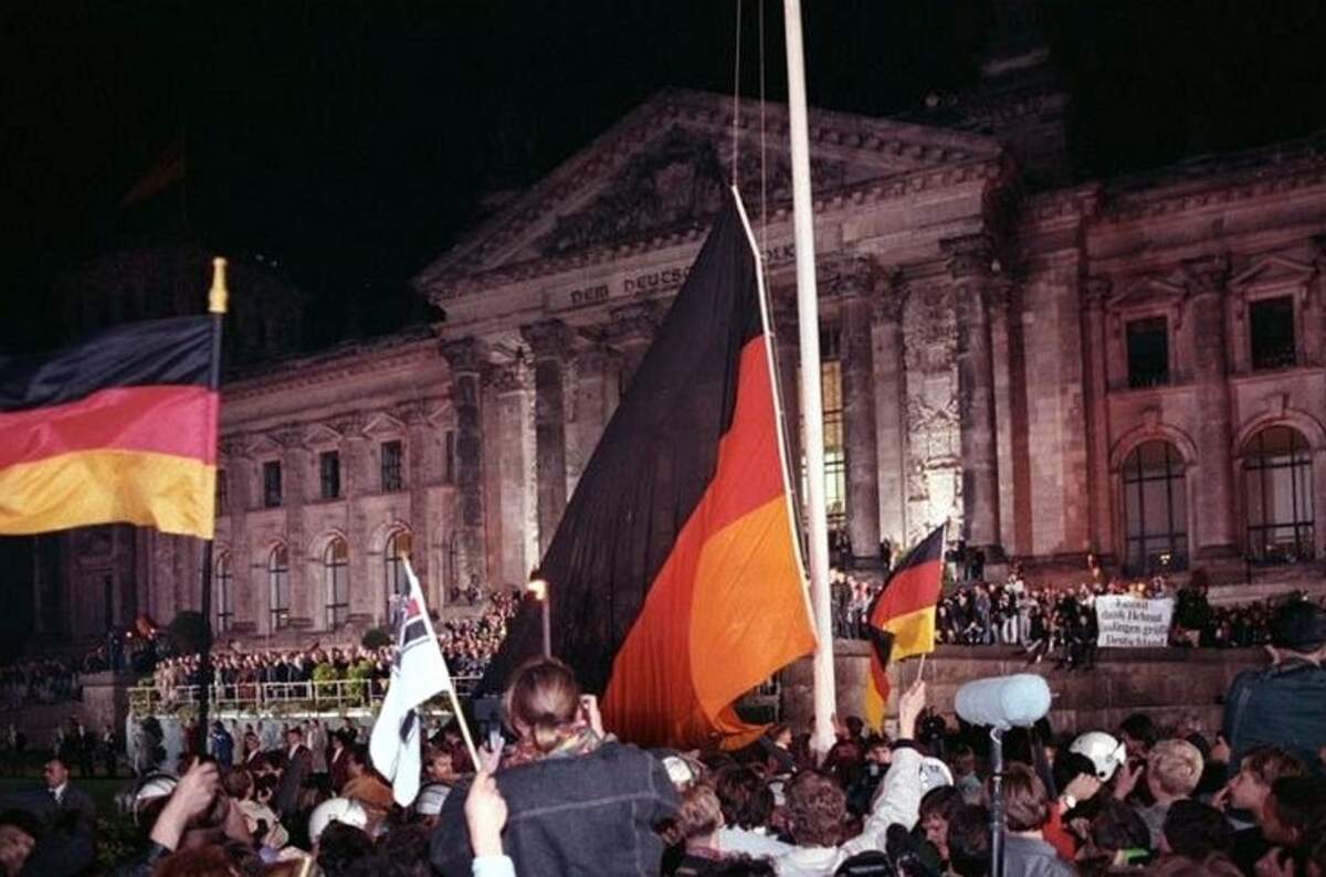 Le drapeau de l’Allemagne réunifiée est hissé le 3 octobre 1990 devant le Reichstag | Via Wikimedia