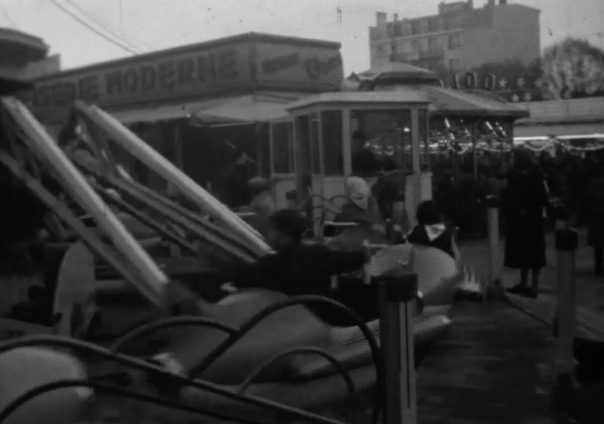 Capture écran de « Manèges et autres stands de forains sur l’esplanade du Champ de Juillet au début des années 1960. »  Cinémathèque de Nouvelle-Aquitaine Date : Années 1960 · Référence :  C P8 DES01 0077 PR
