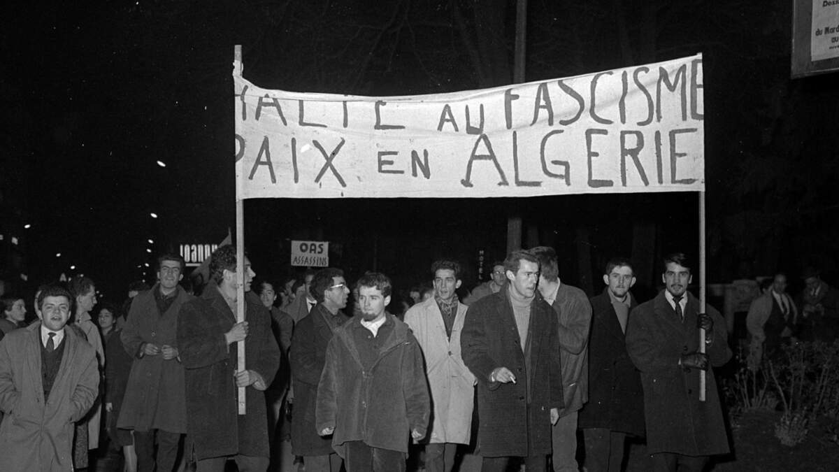 16 janvier 1962. Scène de manifestation : vue de face de manifestants tenant banderole « Halte au fascisme Paix en Algérie ». Vue de nuit. Cliché pris lors d’une manifestation anti OAS (Organisation de l’Armée Secrète) organisée par le font syndical commun.