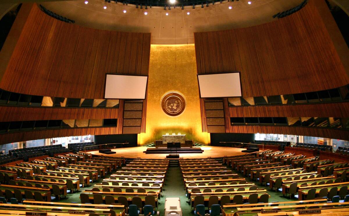 La salle plénière de l’Assemblée générale, utilisée pour la première fois à l’ouverture de sa septième session ordinaire, le 14 octobre 1952. Par Patrick Gruban, cropped and downsampled by Pine   originally posted to Flickr as UN General Assembly, CC BY-SA 2.0, https://commons.wikimedia.org/w/index.php?curid=4806869