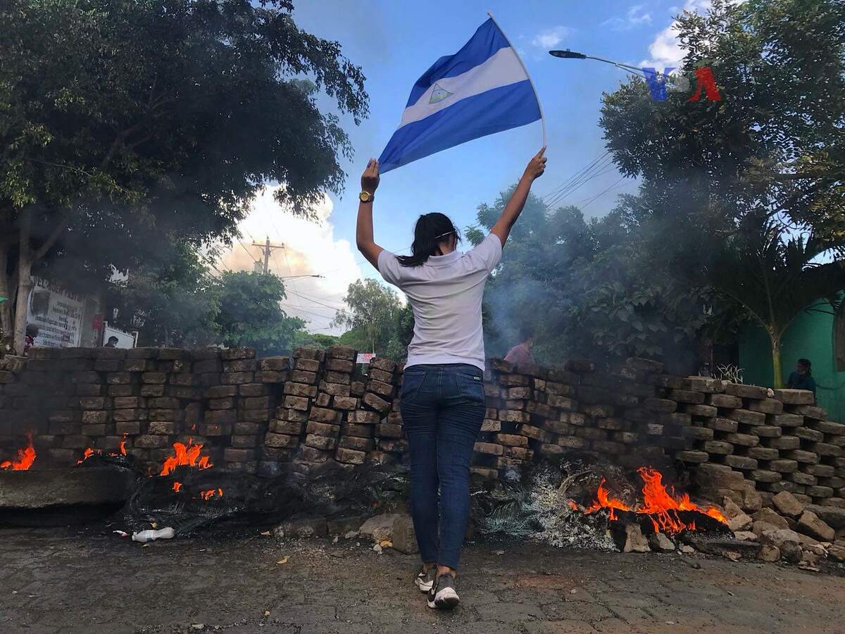 Une manifestante tient le drapeau nicaraguayen près d’une barricade le 20 avril 2018. Wikimédia