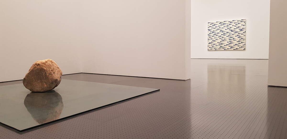 Vue d’exposition, photo Jean-François Bouthors. Relatum, 1970/2019. Pierre et verre. Pierre h : 70 cm, plaque de verre, 240 x 300 x 1,9 cm. Courtesy Kamel Mennour. © Lee Ufan. Et From Point, 1977. Colle et pigment minéral sur toile. 182 x 22